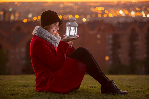 Жизнерадостная женщина на красной зимнее пальто держит фонарь светодиодные фонари