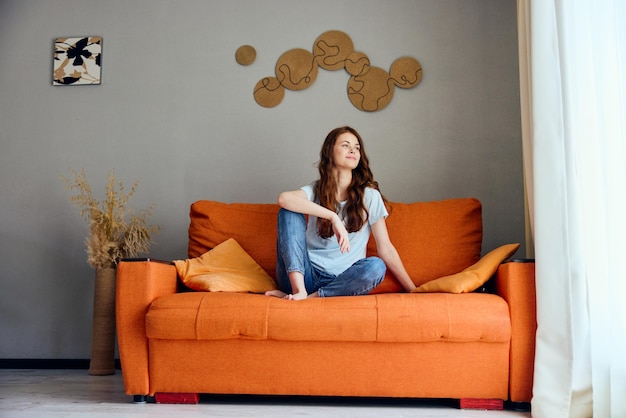 Cheerful woman relaxing at home in the room on the couch interior apartments