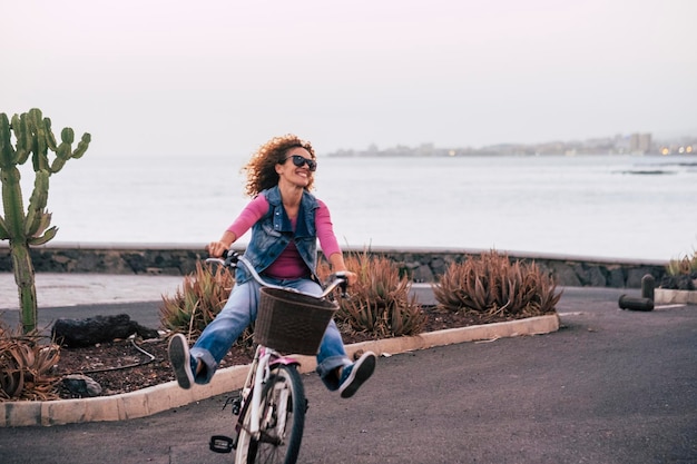 Photo cheerful woman riding bicycle on road against sea