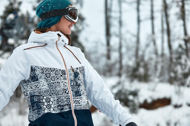 写真 白いスキースーツを着た冬の山でスノーボードに乗っている陽気な女性