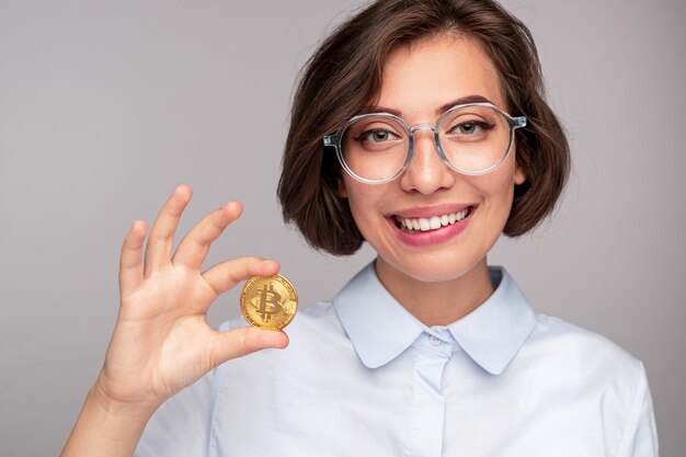 Photo cheerful woman showing bitcoin and smiling