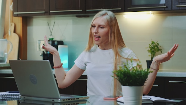 Cheerful woman singing and gesturing while looking on the computer screen