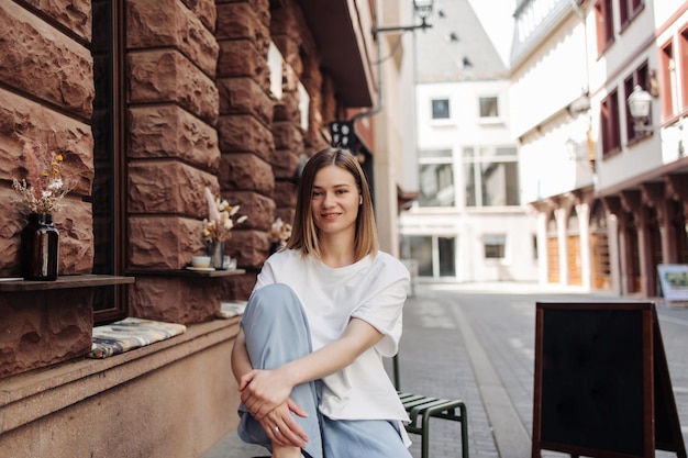 Cheerful woman sitting at cafe in white shirt smiling