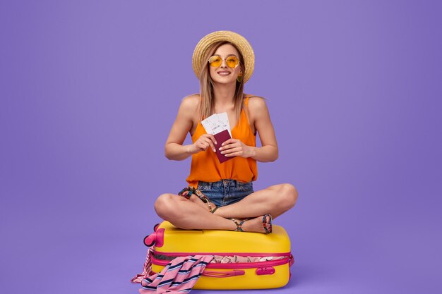 Cheerful woman sitting on luggage before trip