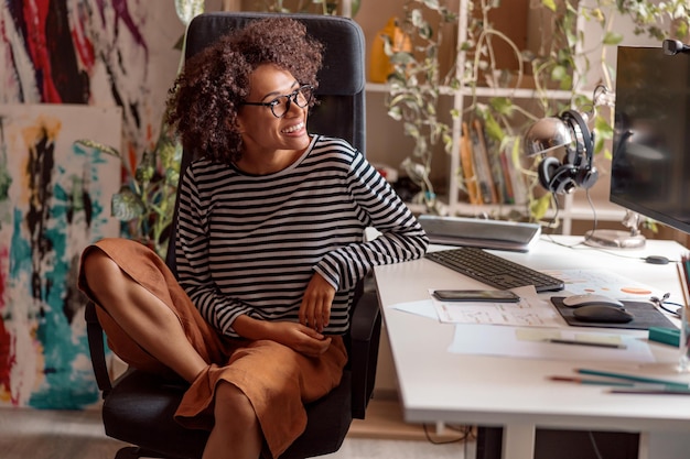 Photo cheerful woman sitting at work table at home