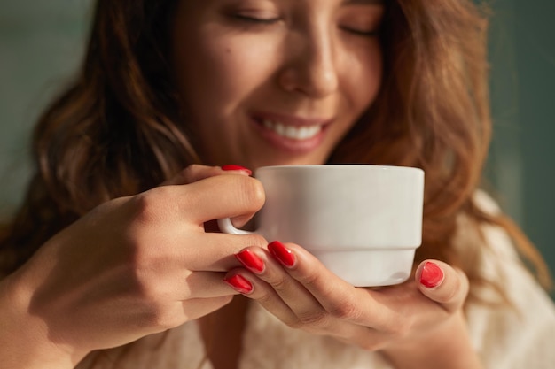 家でコーヒーの匂いを嗅ぐ陽気な女性