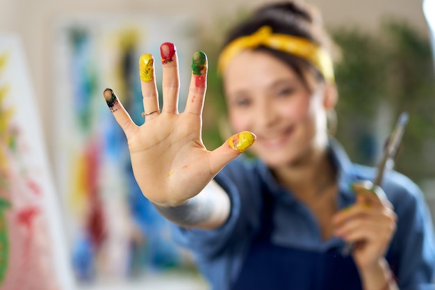 Photo cheerful woman smiling creating abstract painting applying colorful paints on canvas with fingers