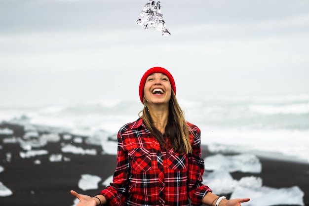 Foto donna allegra in piedi sulla spiaggia durante l'inverno