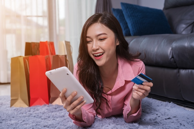 Cheerful woman using digital tablet for online shopping with credit card in living room