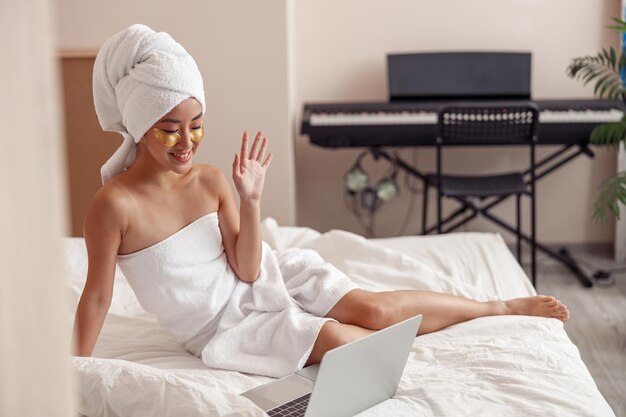 Cheerful woman using laptop for online communication at home