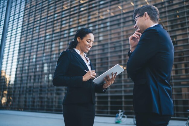 Cheerful woman using tablet while surveying man