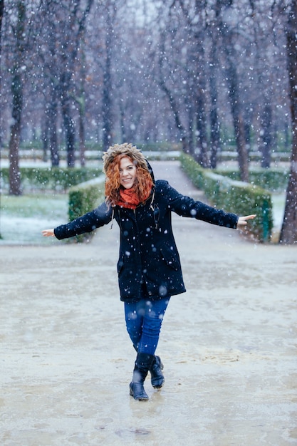 Donna allegra che cammina sotto la neve