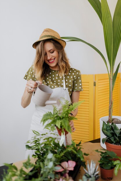 Cheerful woman watering her houseplants