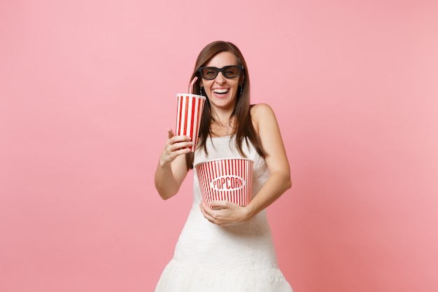 Donna allegra in abito bianco occhiali 3d che guarda film con secchio di popcorn, bicchiere di plastica di soda o cola