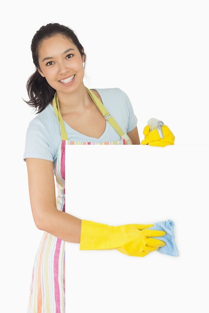 Cheerful woman wiping down white surface