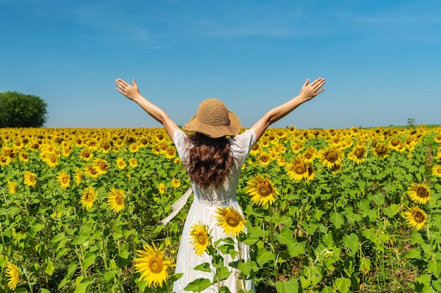 Donna allegra con le braccia alzate e godendo con il campo di girasoli