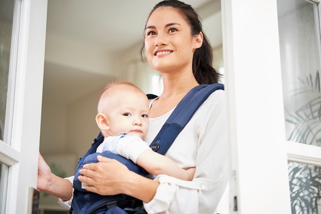 Cheerful woman with baby opening window