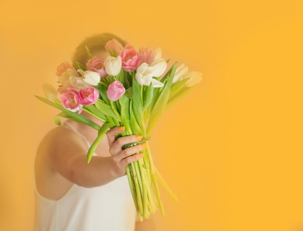 Cheerful woman with bouquet over beige background