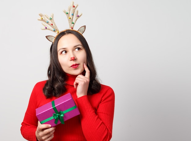 Cheerful woman with christmas deer antlers with gift  