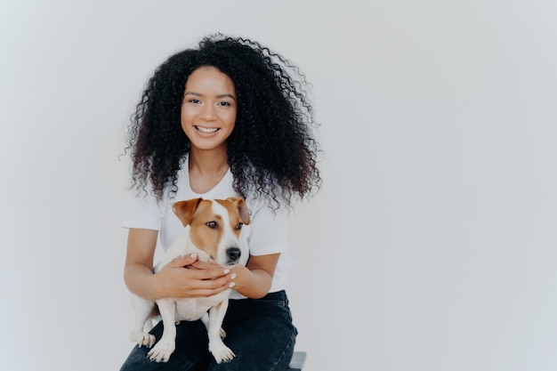 Cheerful woman with crisp hair plays and poses with pedigree dog capturing a memorable moment Humans and animals concept