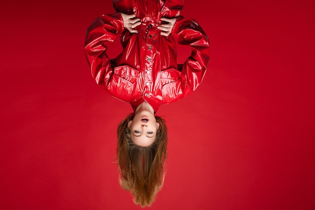 Cheerful woman with fair hair on top in red suit rejoices, picture isolated on red background