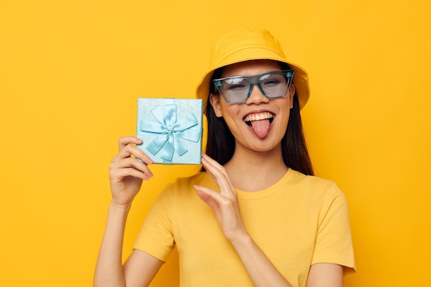 Cheerful woman with gift box in hat and glasses