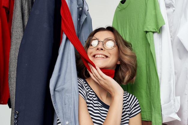 Веселая женщина в очках примеряет магазин одежды шопоголик на светлом фоне
