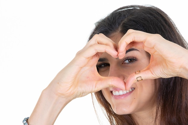 Donna allegra con i capelli lunghi castana che fa la forma del cuore con le dita delle mani con l'occhio marrone