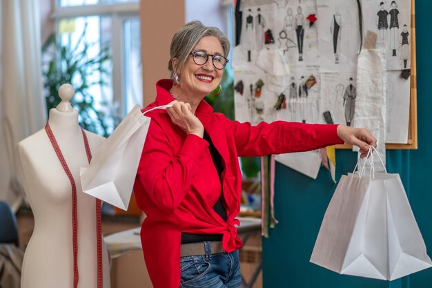 Donna allegra con le borse della spesa che guarda l'obbiettivo