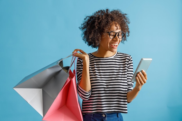 Cheerful woman with shopping bags using mobile phone