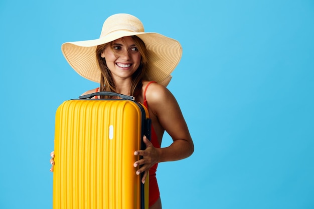 Cheerful woman with stylish hat and yellow suitcase looking ready for a new adventure