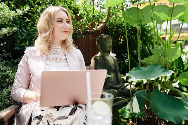 Cheerful woman working on laptop outdoors