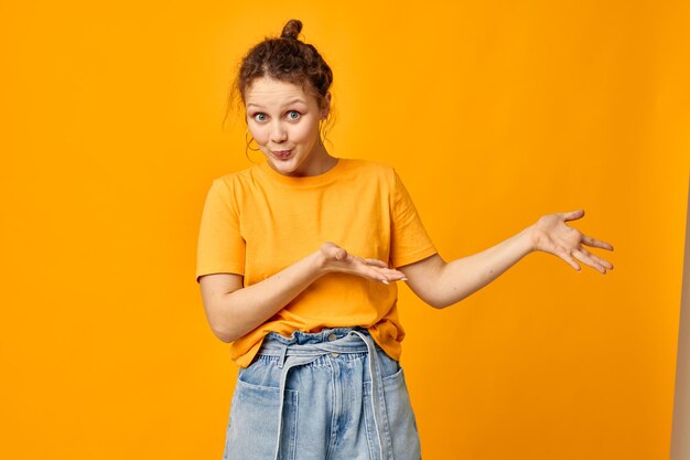 Cheerful woman in a yellow tshirt posing emotions yellow background unaltered
