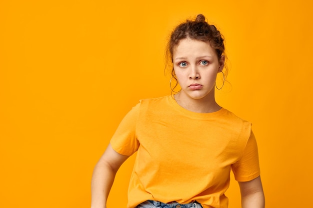 Cheerful woman in a yellow tshirt posing emotions yellow background unaltered