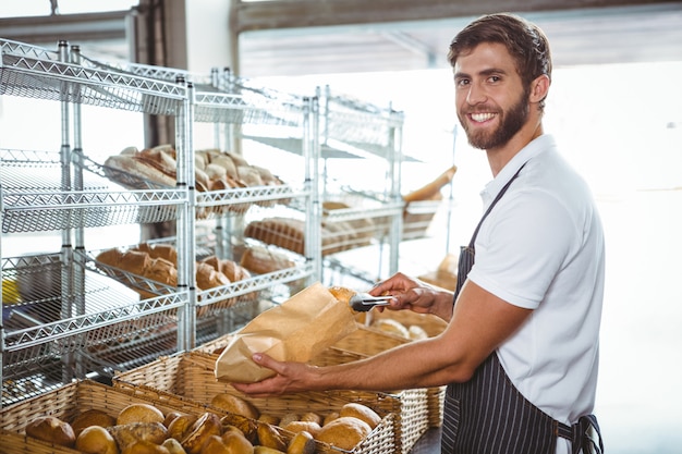 Lavoratore allegro che sta e che presenta un pane