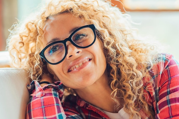 Photo cheerful young adult pretty middle age woman eyewear portrait having fun and smiling at home in bright living room happy female people enjoy indoor resting activity on the sofa and wearing eyeglasses