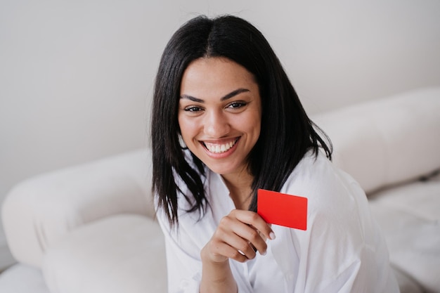 Photo cheerful young african american entrepreneur with straight hair and toothy smile holding credit card