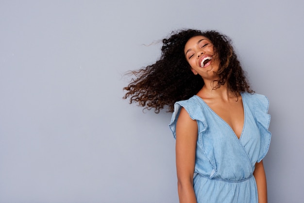 Веселая молодая афро-американская женщина с вьющимися волосами смеется