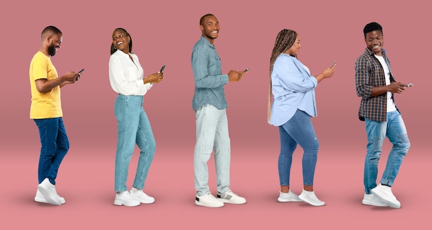 Cheerful young african american women and men in casual typing on smartphones watch video