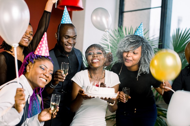 Cheerful young African company celebrates birthday and have a cake with candles