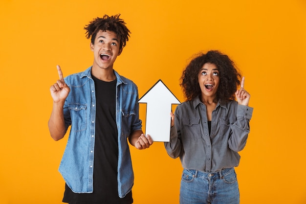 Cheerful young african couple standing isolated, pointing arrow up