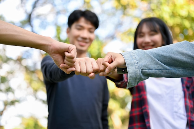 Cheerful young Asian college students showing fist bump together teamwork best friends unity