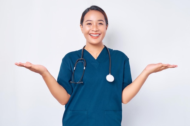 Cheerful young Asian female professional nurse working wearing a blue uniform standing confident with a smiling expression greeting patients isolated on white background Healthcare medicine concept