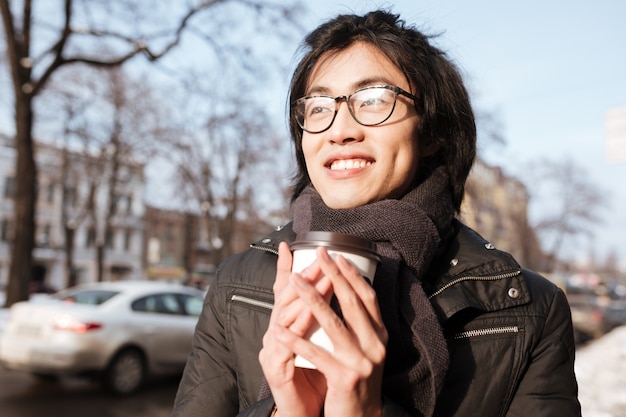 Cheerful young asian man drinking coffee.