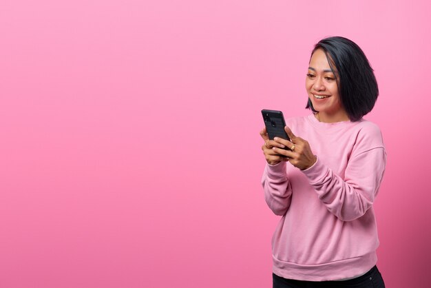 Cheerful young Asian using smartphone with smiling face