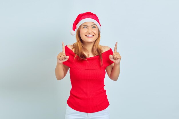 Cheerful young Asian woman pointing fingers up at copy space isolated over white background