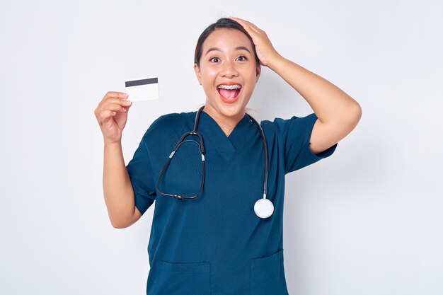 Cheerful young Asian woman professional nurse working wearing blue uniform holding credit bank card isolated on white background Healthcare medicine concept