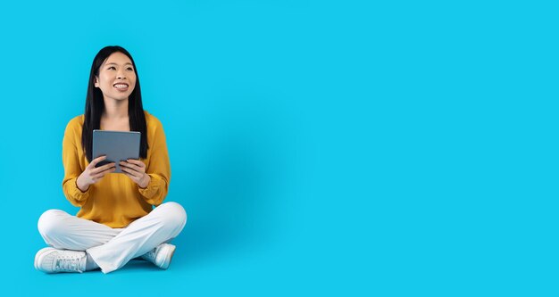 Cheerful young asian woman using digital tablet copy space