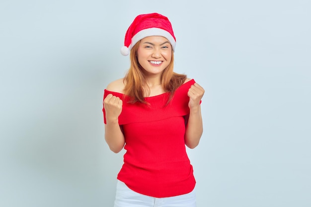 Cheerful young Asian woman wearing christmas dress excited to celebrate christmas over white background