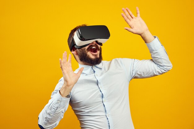 Cheerful young bearded man wearing virtual reality helmet touching the air